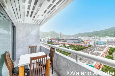 a balcony with a table and chairs and a view at OMNIAPHUKET - Patong Tower - Premium 3 Bedrooms Apartment in Patong Beach