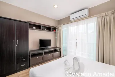 a bedroom with a white bed and a tv at OMNIAPHUKET - Patong Center Pool Gym Near Bangla Road in Patong Beach