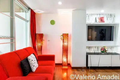 a living room with a red couch and a tv at OMNIAPHUKET - Pool access 3 bedrooms apartment in Patong Beach