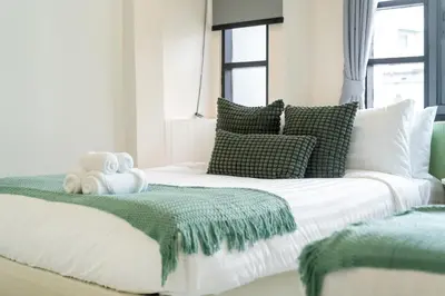 a white bed with green and white pillows at Wink 3 Patong Beach Phuket sleep 8 in Patong Beach