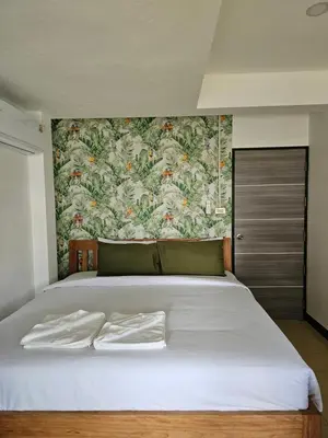 a bedroom with a large white bed with a floral wallpaper at Little Green House in Ao Nang Beach