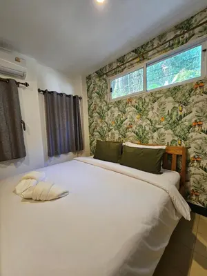 a bedroom with a large white bed with floral wallpaper at Little Green House in Ao Nang Beach