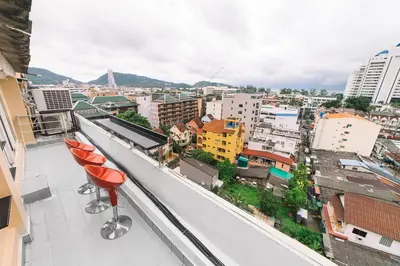 a balcony with two red chairs and a view of a city at Patong Condotel Penthouse 2 bedroom in Patong Beach