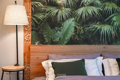 a bedroom with a bed with a painting of palm trees at Cozy Apartment with Pools Near the Beach in Kamala Beach