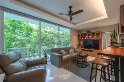 a living room with a couch and a large window at Cozy Apartment with Pools Near the Beach in Kamala Beach