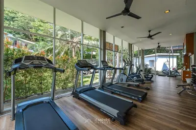 a gym with a row of treadmills and elliptical machines at Cozy Apartment with Pools Near the Beach in Kamala Beach