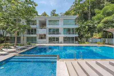 an apartment building with a swimming pool in front of it at Cozy Apartment with Pools Near the Beach in Kamala Beach