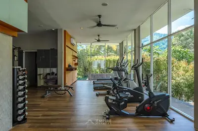a gym with treadmills and exercise bikes in a room at Cozy Retreat Near Beach and Pools in Kamala Beach