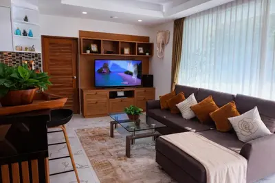 a living room with a couch and a tv at Cozy Retreat Near Beach and Pools in Kamala Beach