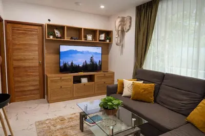 a living room with a couch and a tv at Cozy Retreat Near Beach and Pools in Kamala Beach