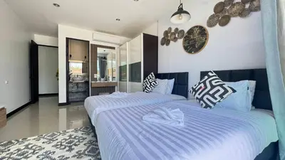 a bedroom with two beds and a clock on the wall at Ban Khuendee Pool Villa in Kathu
