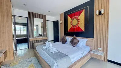 a bedroom with a bed and a painting on the wall at Ban Khuendee Pool Villa in Kathu