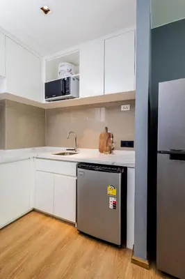 a kitchen with white cabinets and a stainless steel refrigerator at Suite Elio 1BR PoolsGym Shuttle to Nai Harn in Rawai Beach