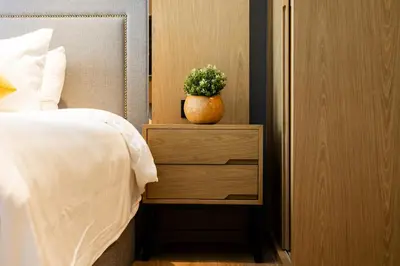a plant in a vase on a night stand next to a bed at Suite Elio 1BR PoolsGym Shuttle to Nai Harn in Rawai Beach