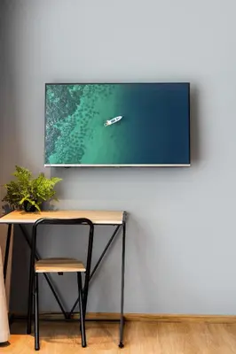 a tv hanging on a wall next to a desk at Suite Elio 1BR PoolsGym Shuttle to Nai Harn in Rawai Beach