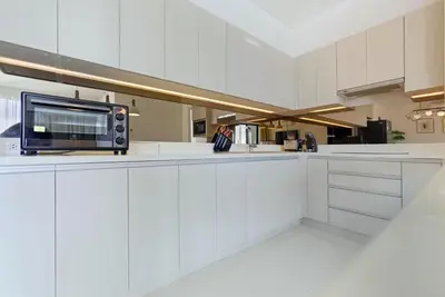 a kitchen with white cabinets and a microwave at Suite Velora 3BR Pool GymCassia Laguna Phuket in Laguna Phuket