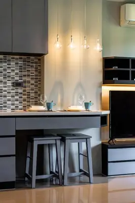 a kitchen with a counter with two stools in it at Suite Ruse 1BR Rooftop Pool ViewCitygate Kamala in Kamala Beach
