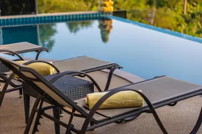 a table and chairs next to a swimming pool at Karon Bliss Sea View Villa with Private Pool in Karon Beach