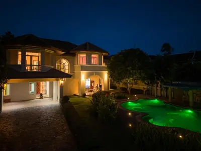 a house with a green yard at night at Sundrenched Oasis 7bed pool villa heart of Phuket in Kathu