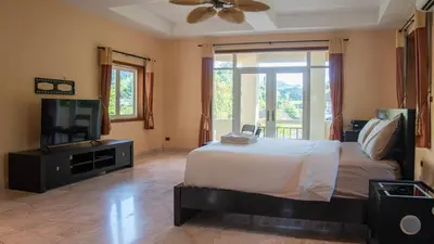 a bedroom with a bed and a flat screen tv at Sundrenched Oasis 7bed pool villa heart of Phuket in Kathu