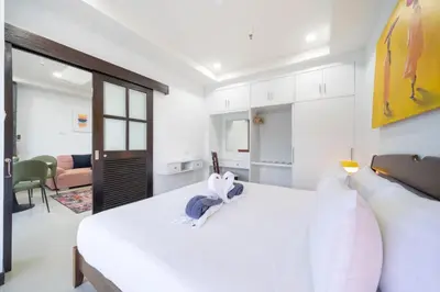 a bedroom with a large white bed and a living room at Apartment with jacuzzi - Patong Tower by lofty in Patong Beach