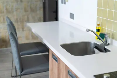 a kitchen counter with a sink and two chairs at Private apartment at Twin Sands near Merlin beach in Patong Beach