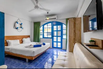 a bedroom with a bed and a couch and a window at La Casa Residencies in Patong Beach