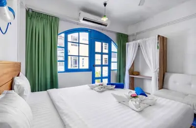 a bedroom with two beds and a window with green curtains at La Casa Residencies in Patong Beach