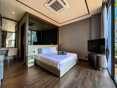 a bedroom with a bed and a flat screen tv at The Ozone Luxury Villas Phuket in Laguna Phuket
