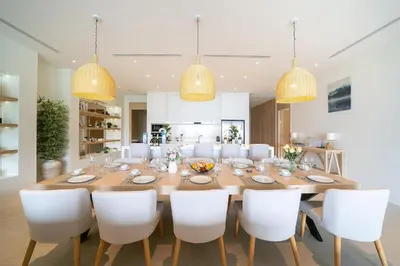 a dining room with a large wooden table and white chairs at The Exclusive Sky D4 \u8c6a\u534e4\u5367\u5ba4\u6d77\u666f\u522b\u5885 \u79c1\u4eba12m\u65e0\u8fb9\u6d77\u666f\u6cf3\u6c60 \u6bcf\u65e5\u6e05\u6d01 in Kamala Beach