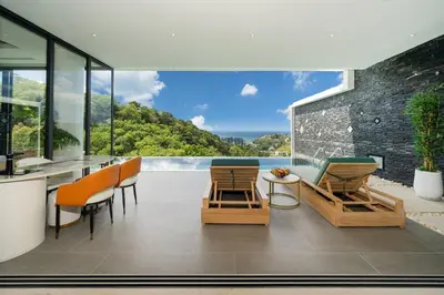 a patio with chairs and a table with a view at The Exclusive Sky D4 \u8c6a\u534e4\u5367\u5ba4\u6d77\u666f\u522b\u5885 \u79c1\u4eba12m\u65e0\u8fb9\u6d77\u666f\u6cf3\u6c60 \u6bcf\u65e5\u6e05\u6d01 in Kamala Beach