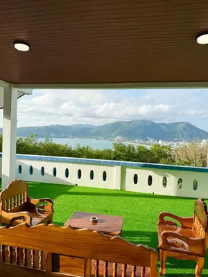 a patio with a table and chairs and a large window at Villa Seaview Patong in Patong Beach
