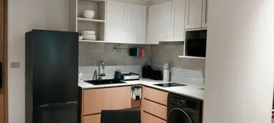 a kitchen with white cabinets and a black refrigerator at Private garden Laguna beachside 150 m Bangtao in Bang Tao Beach