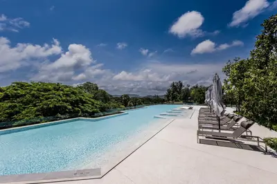 a large swimming pool with chairs and umbrellas at Private garden Laguna beachside 150 m Bangtao in Bang Tao Beach