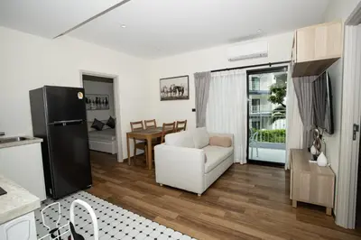 a living room with a white chair and a kitchen at ME5 Halo 2-bedroom ВатСaп66935B2I976 вид на бассейн in Nai Yang Beach