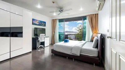 a bedroom with a bed and a desk and a window at Sea view apartment in Phuket in Patong Beach