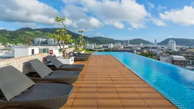a swimming pool on the roof of a building with chairs at Sea view apartment in Phuket in Patong Beach