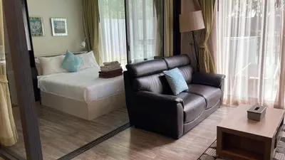 a living room with a leather couch and a bed at The deck patong 2bedroom in Patong Beach