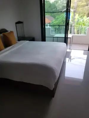 a white bed in a room with a large window at KK Apartment BangJo, Phuket in Koh Lone