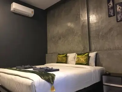 a bedroom with a large white bed with green pillows at Finlay Cottage Aonang in Ban Khlong Haeng