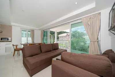a living room with two brown couches and a kitchen at Kata Ocean View I05 in Karon Beach
