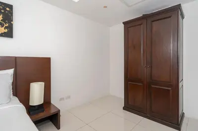 a bedroom with a bed and a wooden cabinet at Kata Ocean View I05 in Karon Beach