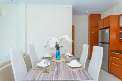 a dining room table with white chairs and a blue vase with flowers at Villa with Private Pool in Rawai in Rawai Beach
