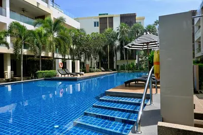 a swimming pool with blue stairs and an umbrella at The Pelican Suite Residence Condo Klong Muang, Krabi in Klong Muang Beach