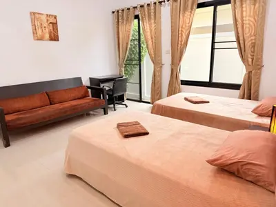 a hotel room with two beds and a couch at BlueElephant Villa NaiHarn in Rawai Beach