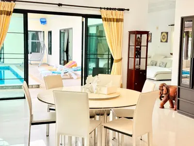a living room with a dining table and a dog at BlueElephant Villa NaiHarn in Rawai Beach