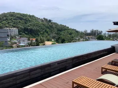 a large swimming pool with two chairs and avisorvisor at Superb Apartment! 5 Mins to the Beach in Surin Beach