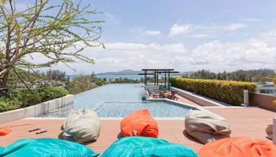 a group of people sitting on a deck next to a swimming pool at Superb Apartment! 5 Mins to the Beach in Surin Beach