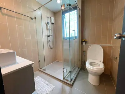 a bathroom with a toilet and a glass shower at Centrio 2 Bedrooms Condos in Town-Central Phuket in Ban Rangeng