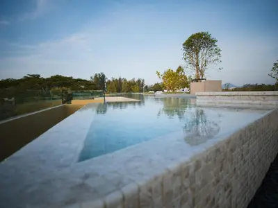 a large swimming pool with a stone retaining wall at Lux apartment 100 sqm in Laguna in Bang Tao Beach